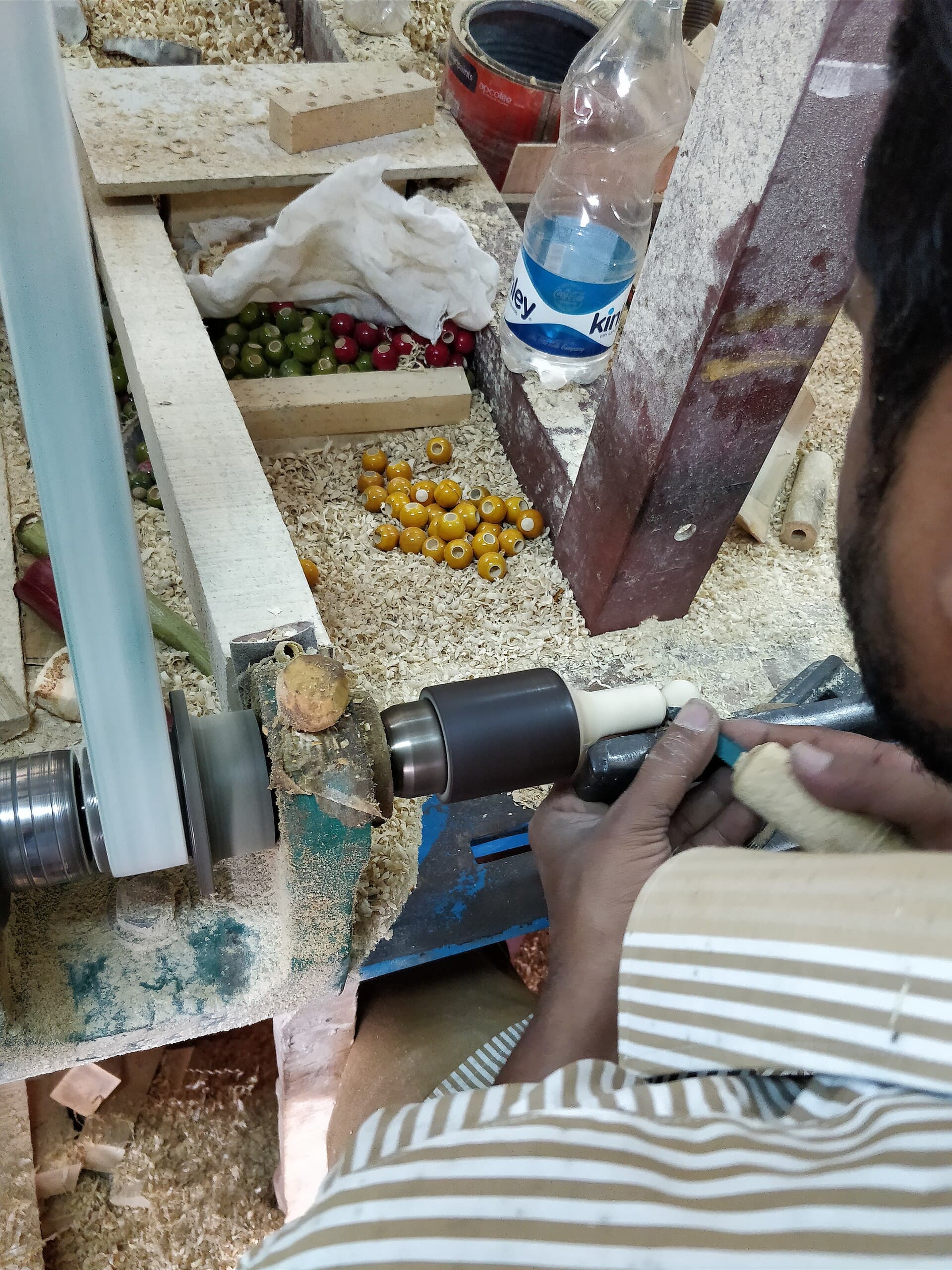A craftsman working a piece of wood on a lathe, shaping a toy.