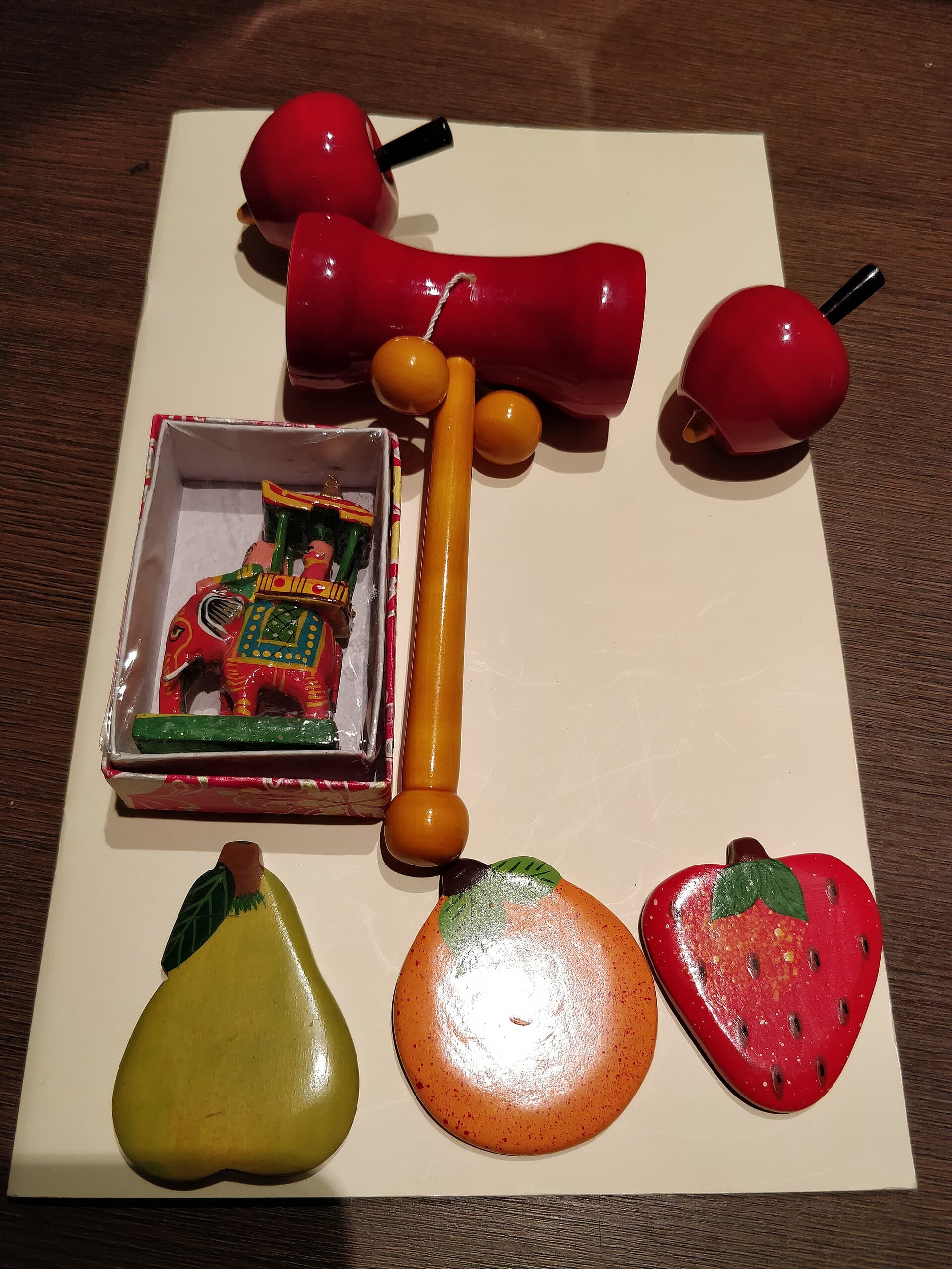 Brightly lacquered wooden toys — fruit shapes, a rattle and a painted elephant.
