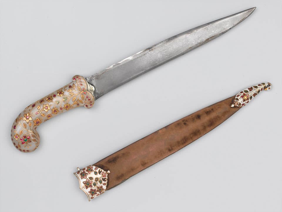 A khanjar of Tipu Sultan: a curved steel dagger with a pale jade hilt inlaid with gold flowers set with rubies and emeralds, beside its velvet-covered scabbard with jewelled mounts.