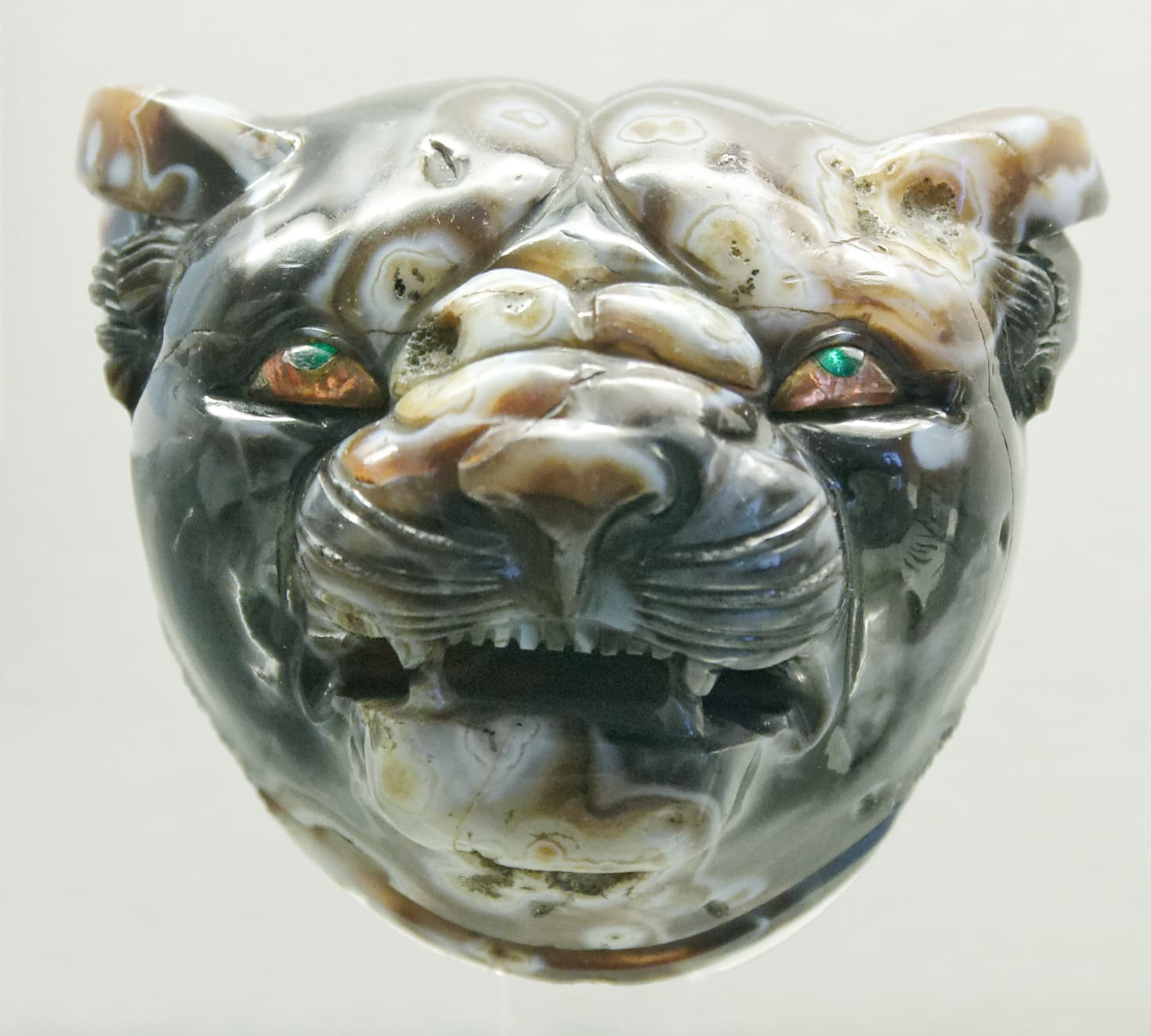 A gold tiger's head with bared teeth and inlaid eyes, made as a fitting for a throne.